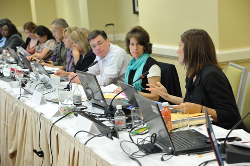 People sitting at a long table with laptops