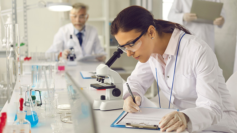 Photo of a female scientist looking into a microscope