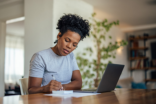 woman taking notes in front of her laptop